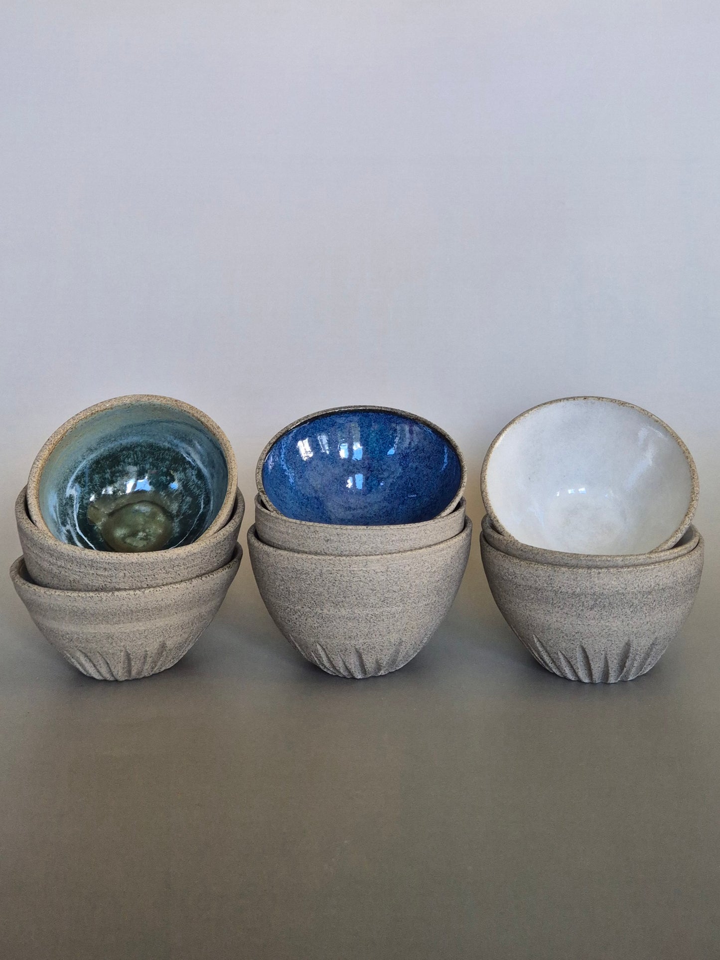 Set of ceramic bowls in various colors on a gray background