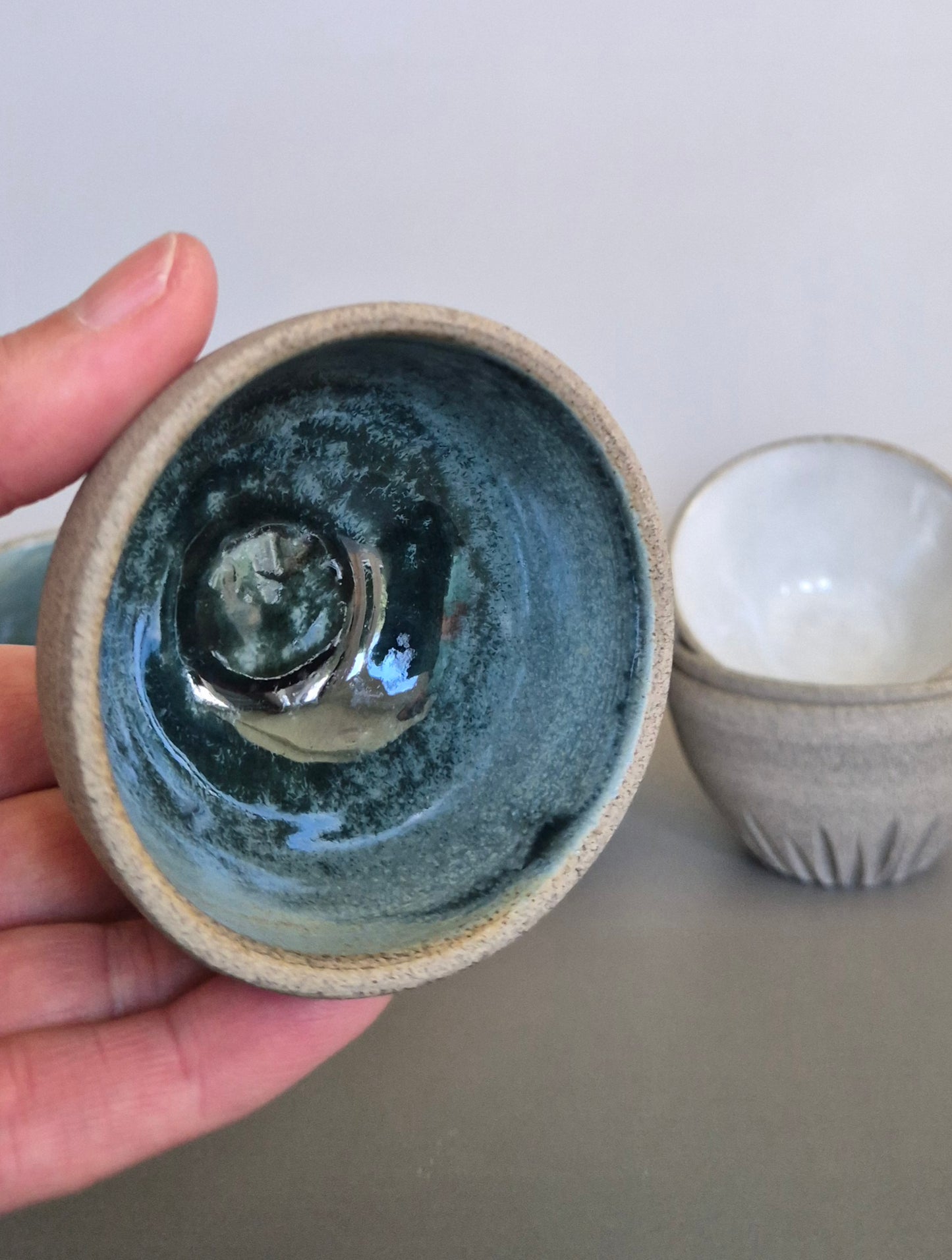 Hand holding a ceramic bowl with a textured surface on a plain background