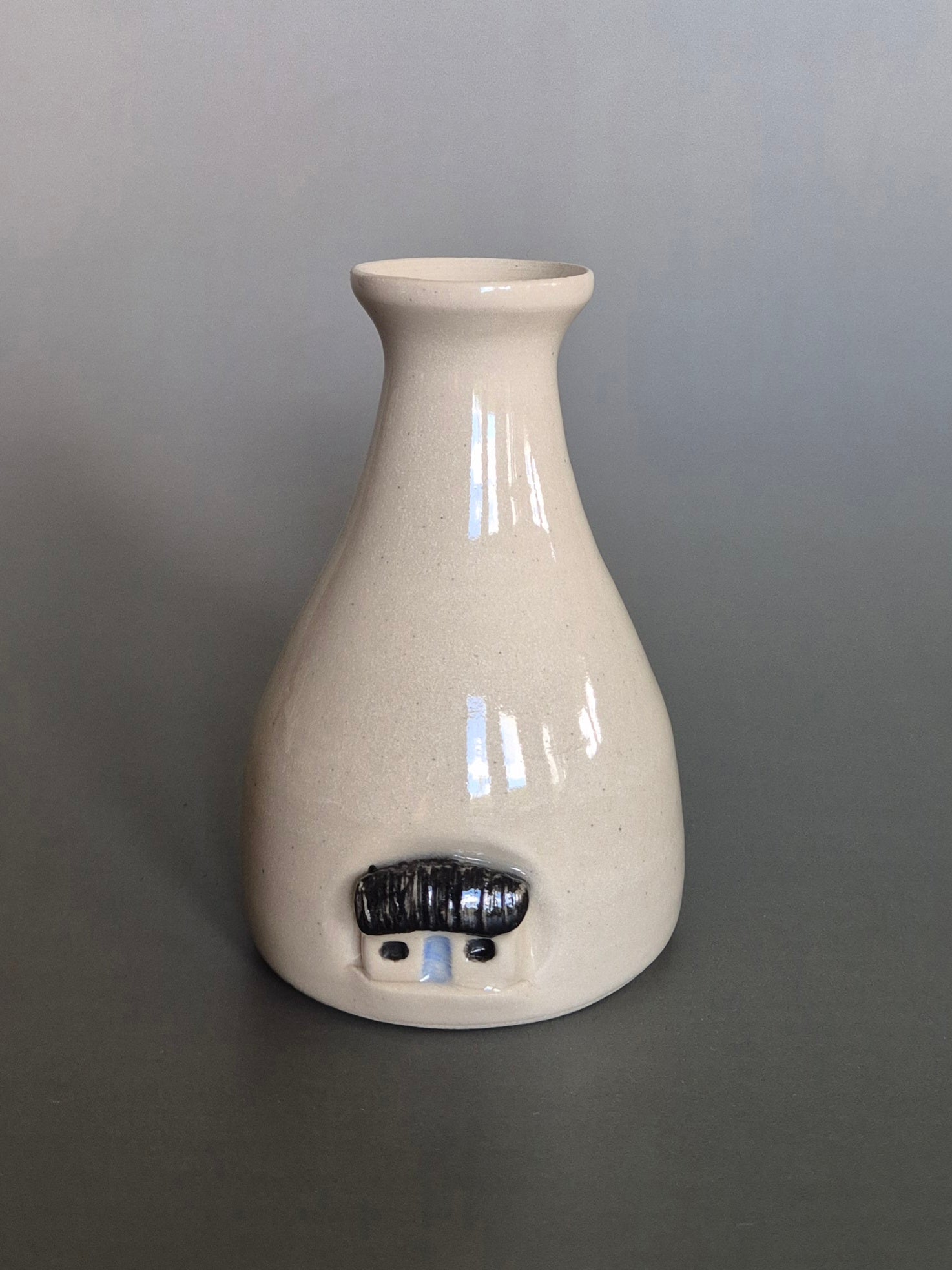 Small white ceramic bottle or bud vase. On a plain background