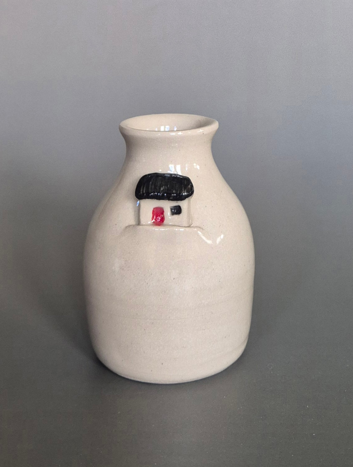 Small white ceramic bottle or bud vase. On a plain background