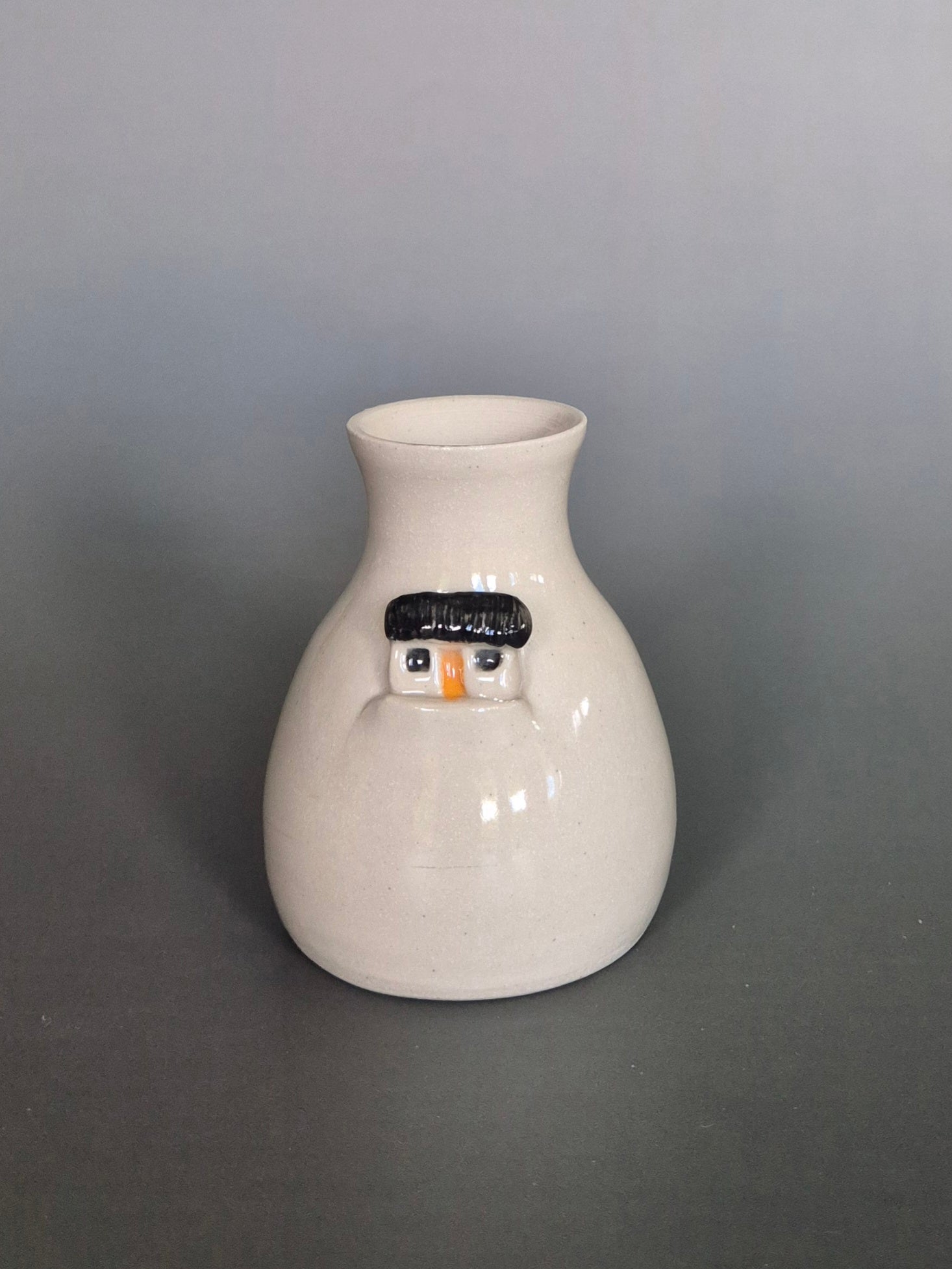 White ceramic vase with a house design on a gray background