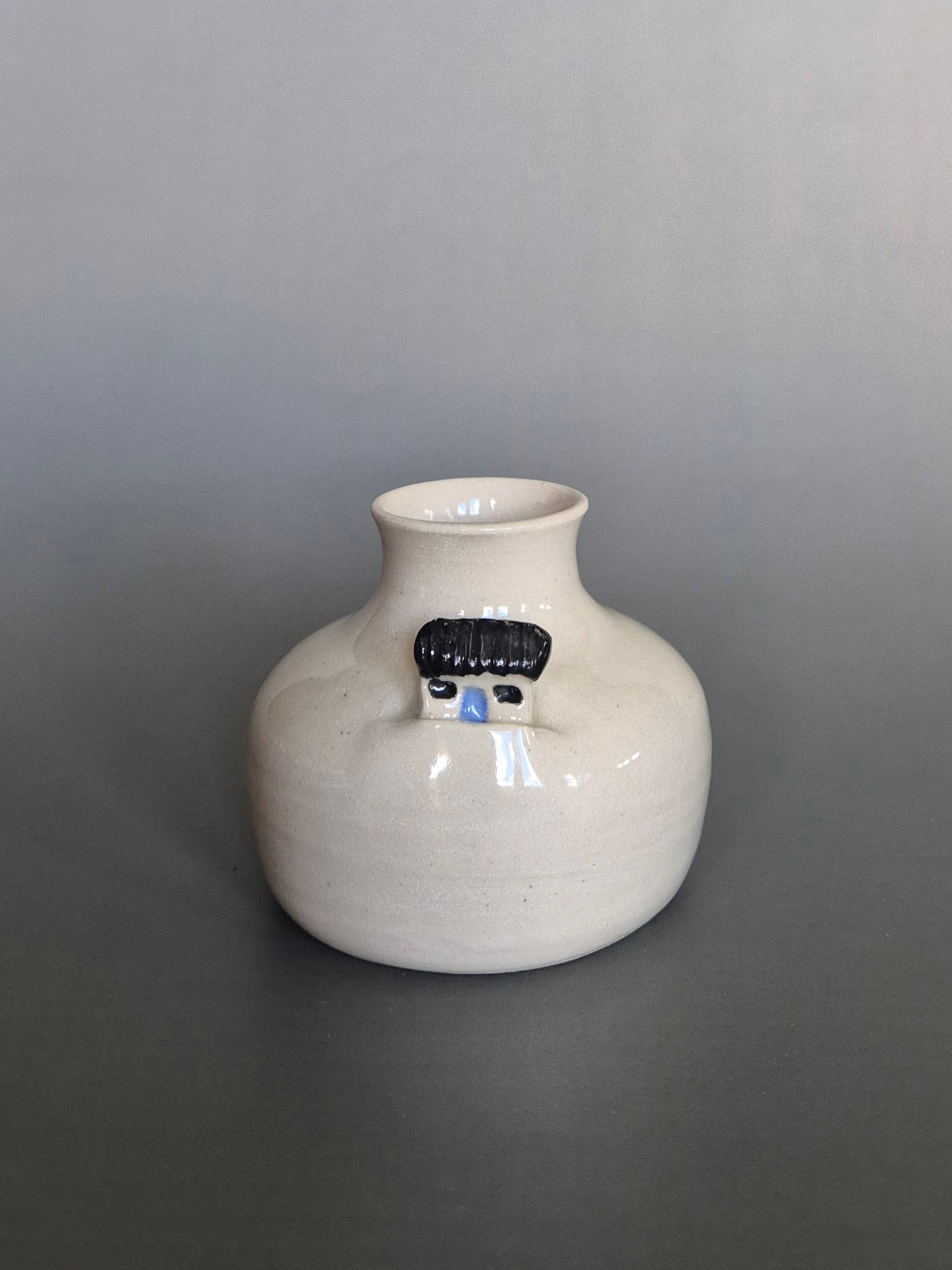 Small white ceramic bottle or bud vase. On a plain background