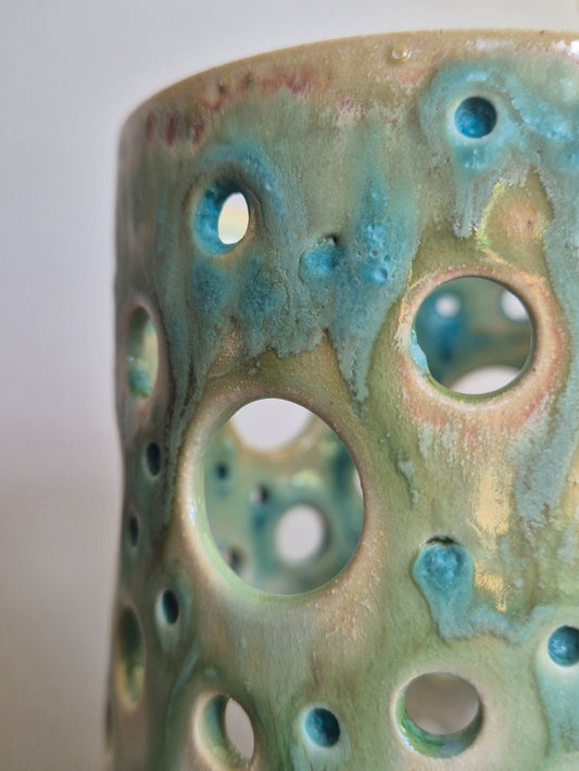 Close-up of a ceramic vase with textured surface and circular holes.