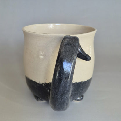 Ceramic cat mug with a black tail handle on a gray background