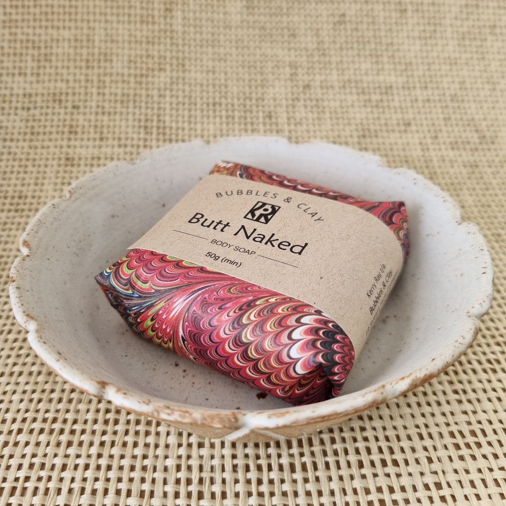 Bar of soap with colorful packaging and 'Butt Naked' text on a textured surface