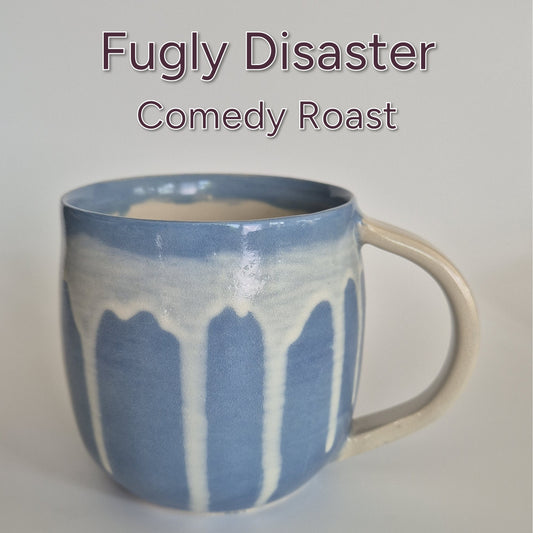 Blue ceramic mug with white glaze on a plain background, featuring text 'Fugly Disaster Comedy Roast'.