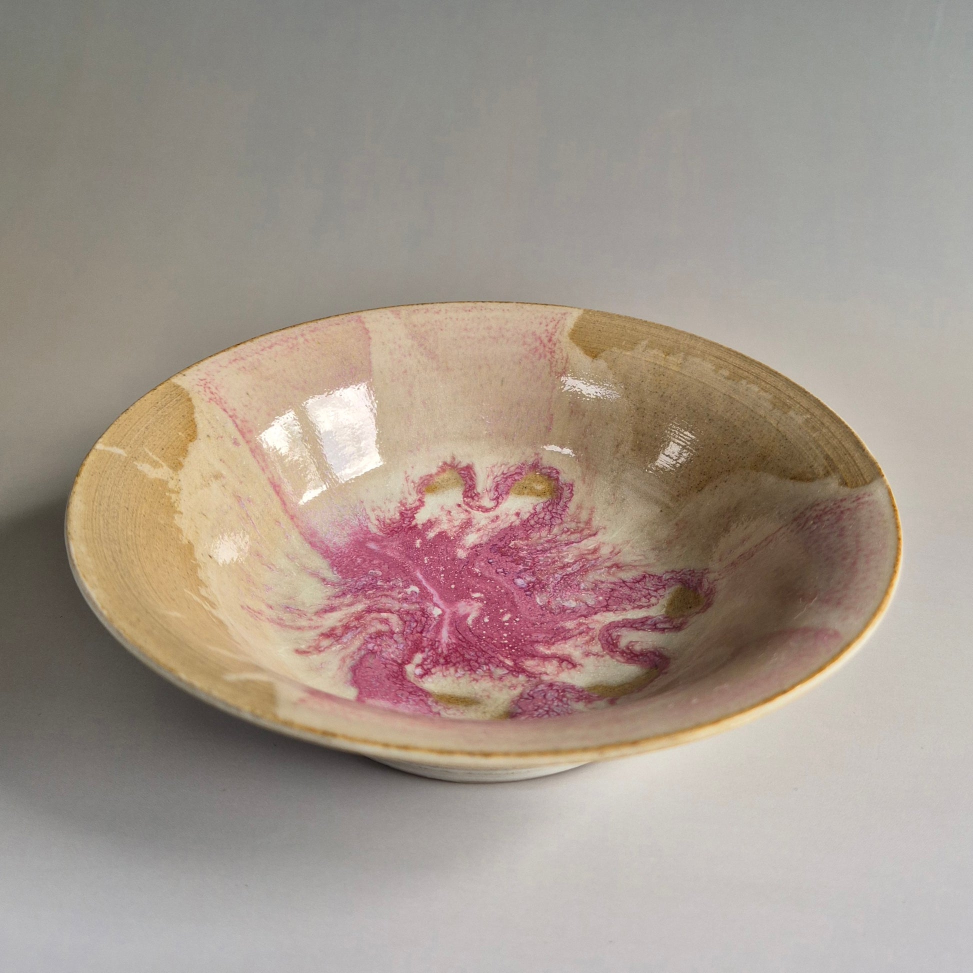 Ceramic bowl with pink and green abstract design on a gray background