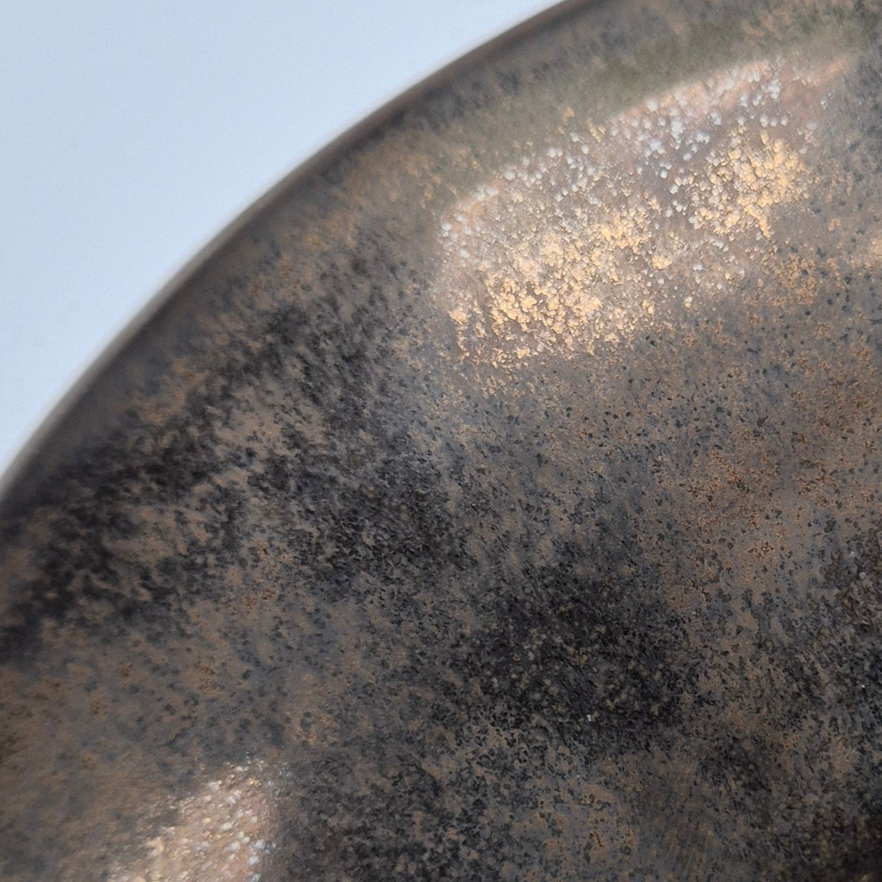 Close-up of a textured metallic glaze surface with a gradient from dark to light.