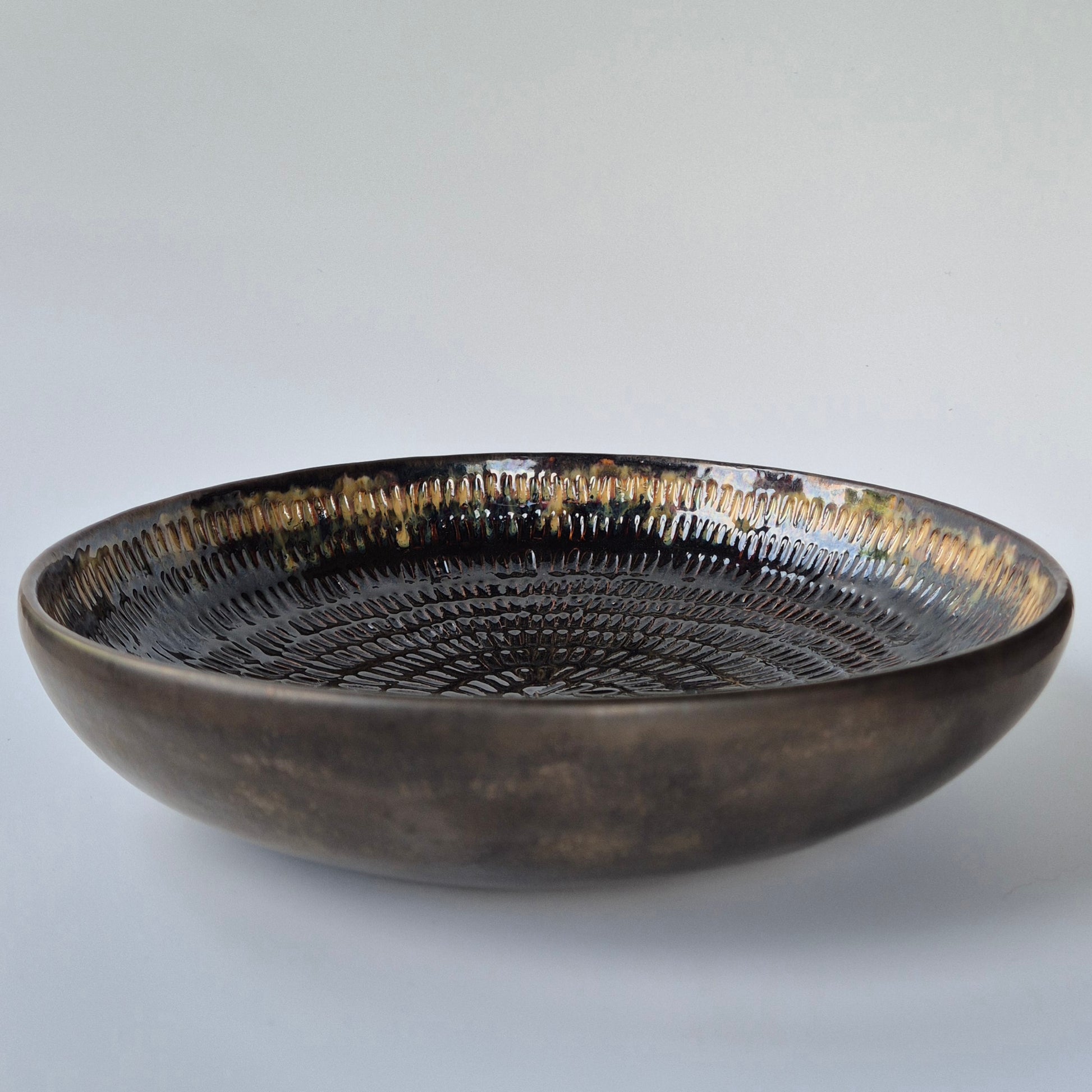 Black ceramic bowl with textured surface on a light gray background