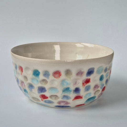 Ceramic bowl with colorful dot pattern on a gray background