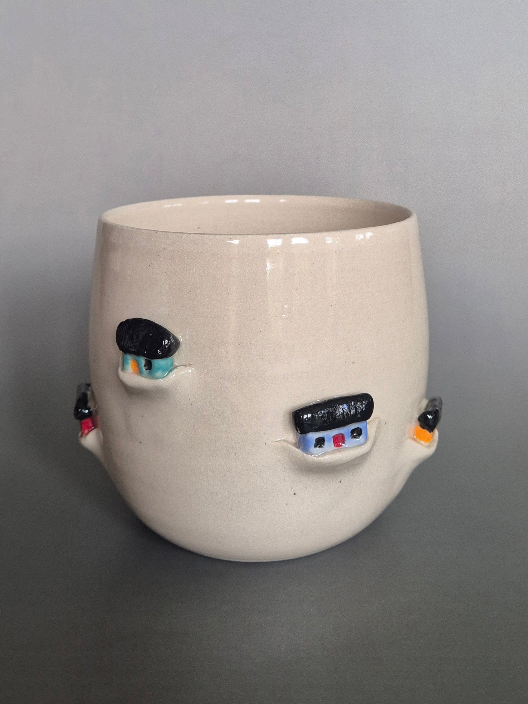 Ceramic pot with tiny sculptural houses on a gray background