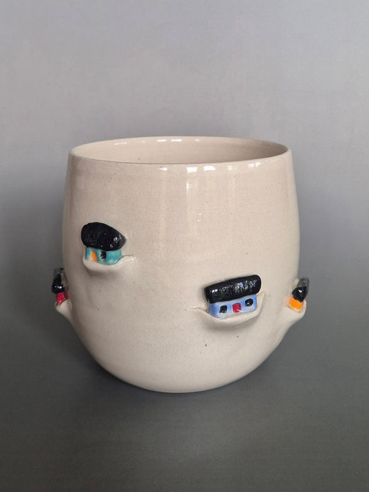 Ceramic pot with tiny sculptural houses on a gray background