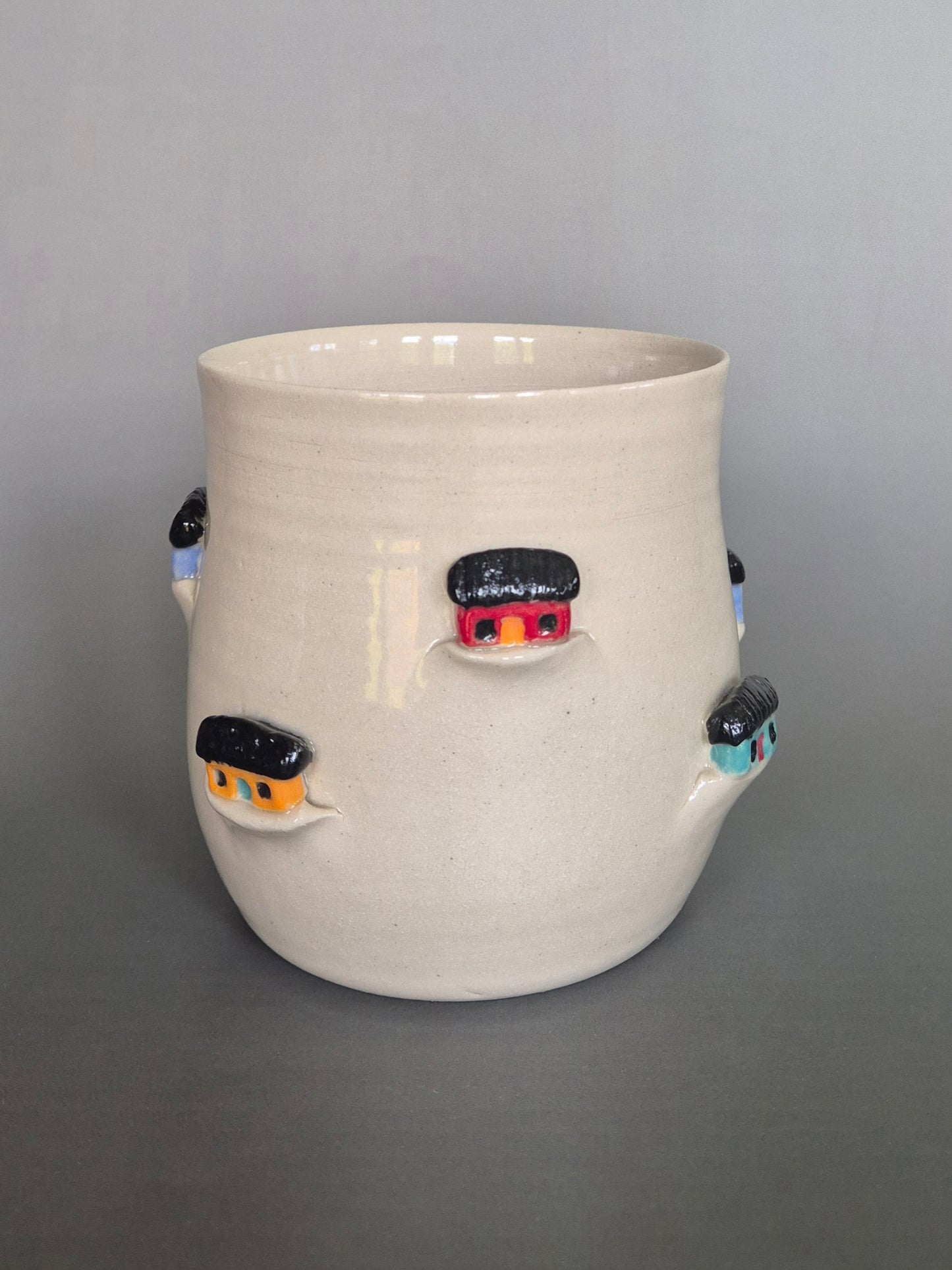Ceramic vase with small houses on a gray background