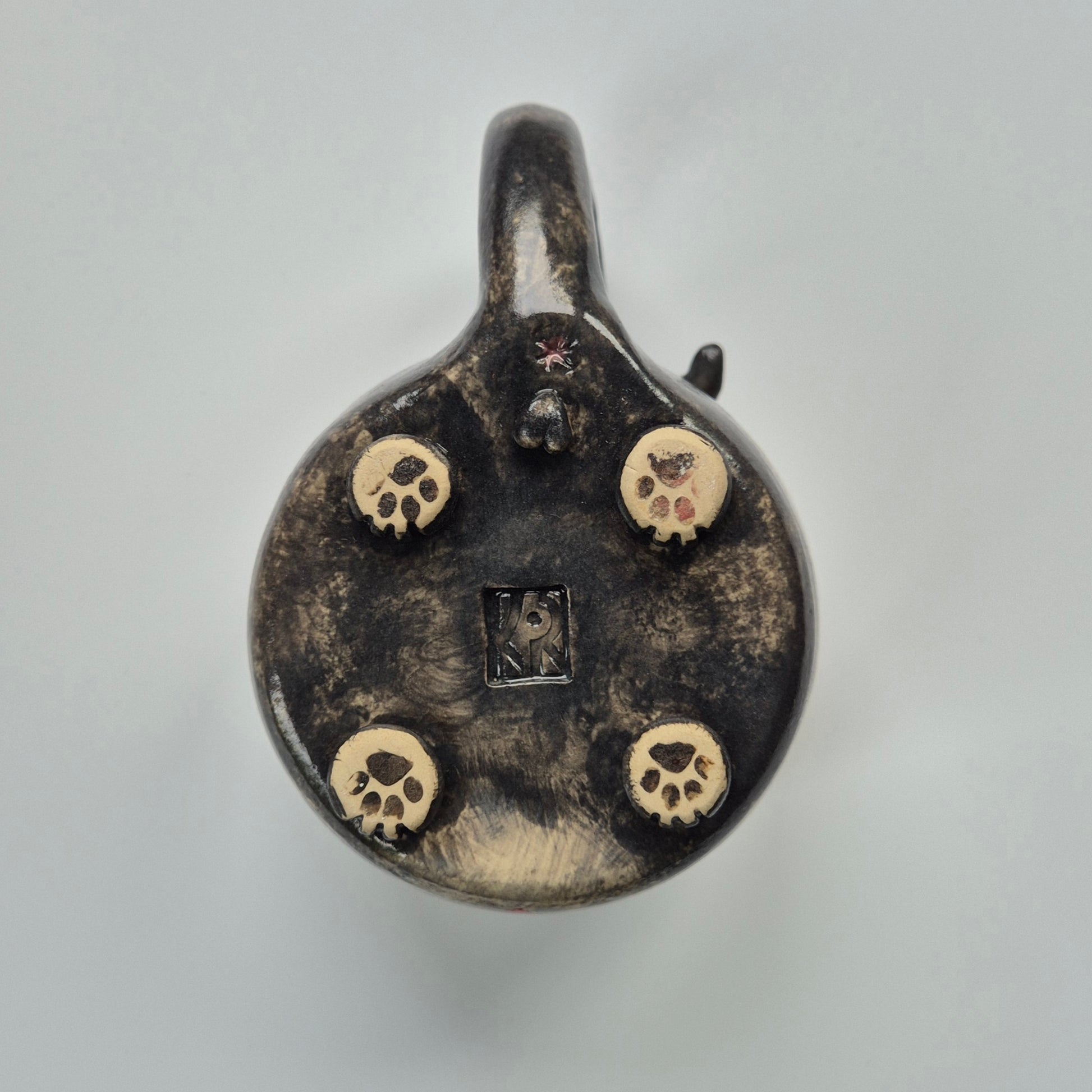 Black ceramic cat mug base showing paw details on a gray background