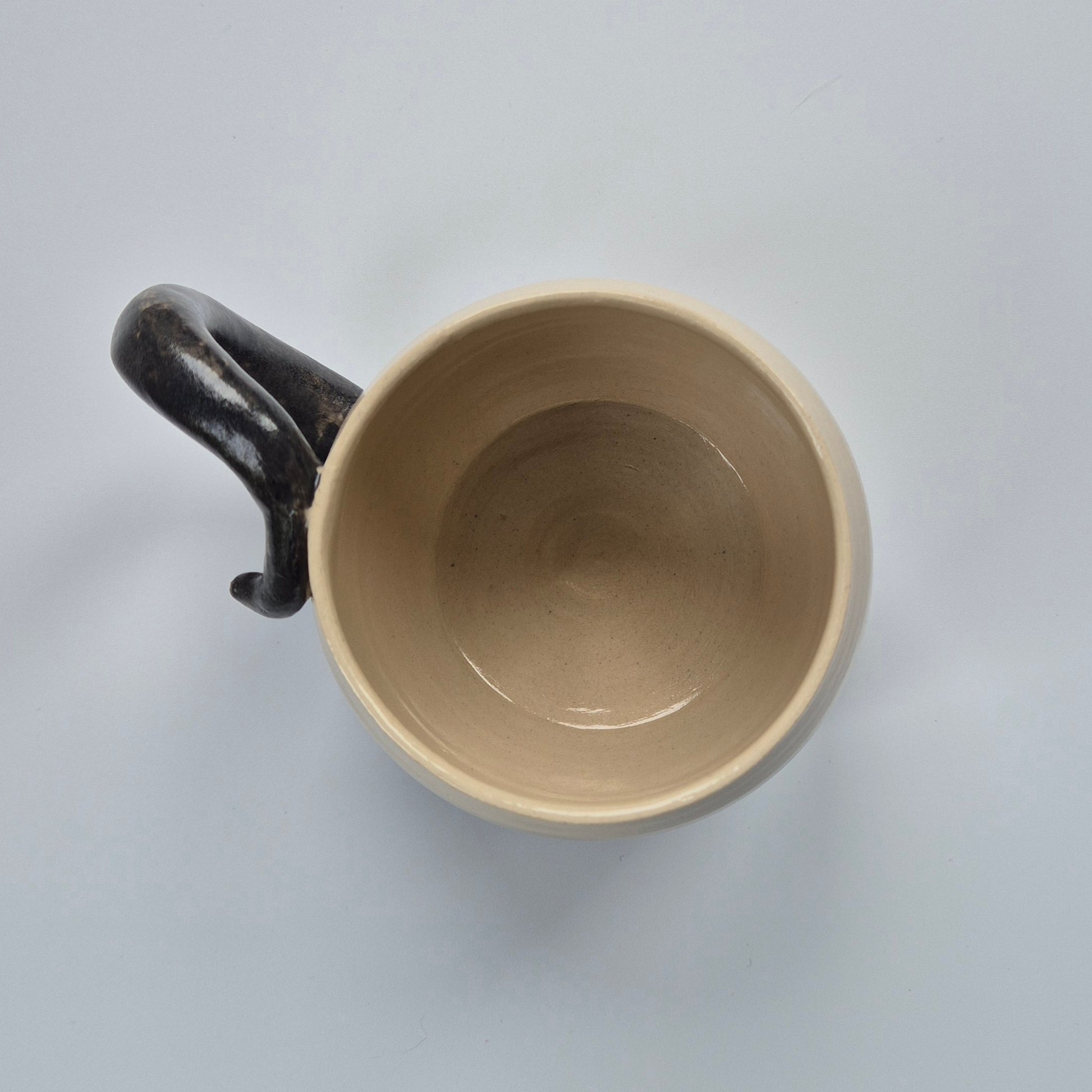 Ceramic mug with a black handle on a light gray background