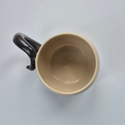 Ceramic mug with a black handle on a light gray background