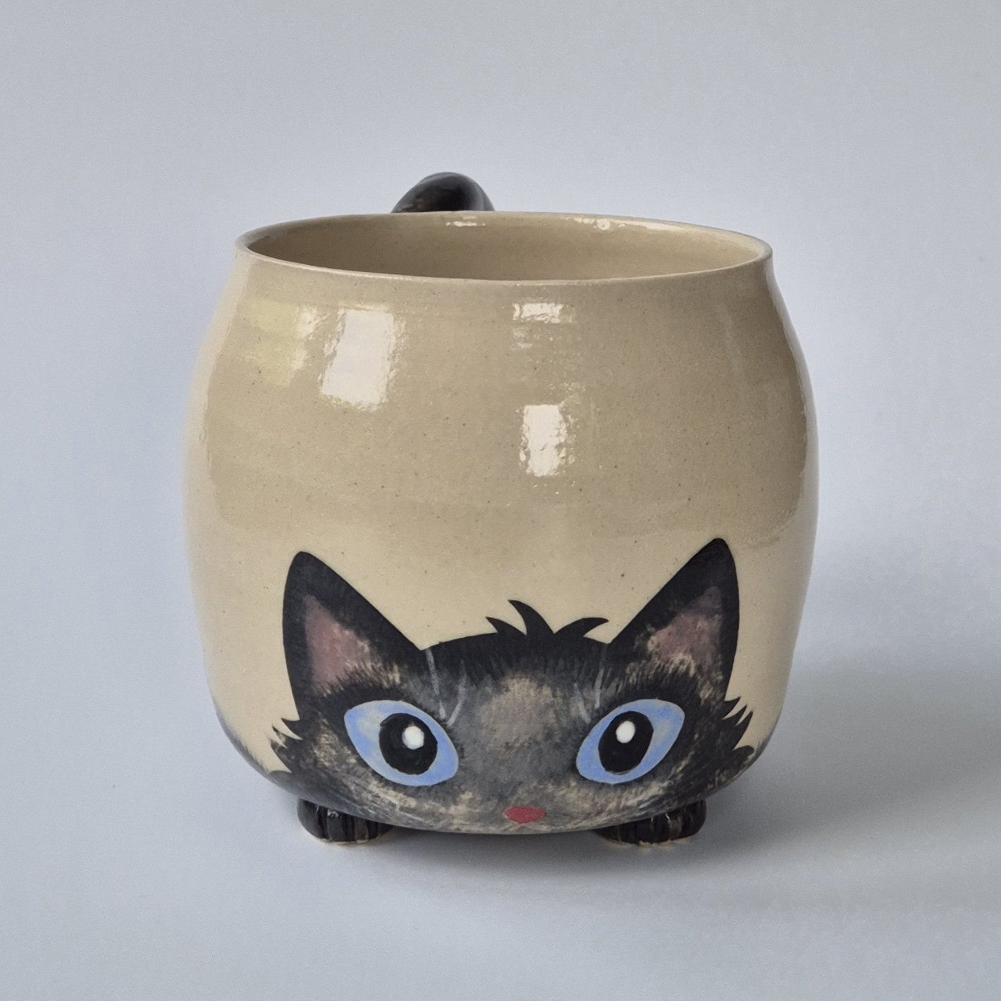 Ceramic mug with a cat design on a plain background