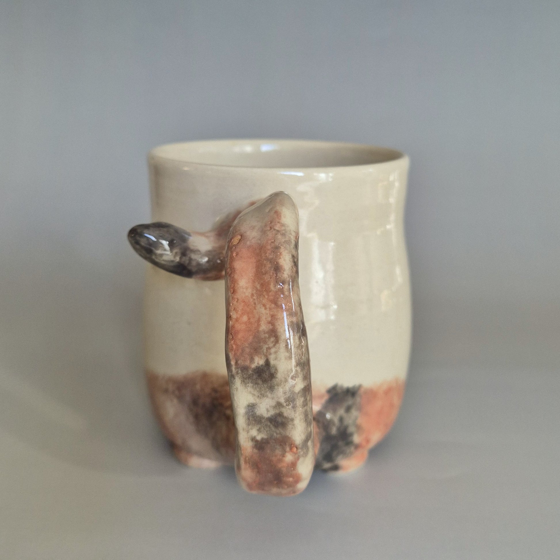 Ceramic mug with a unique handle on a plain background