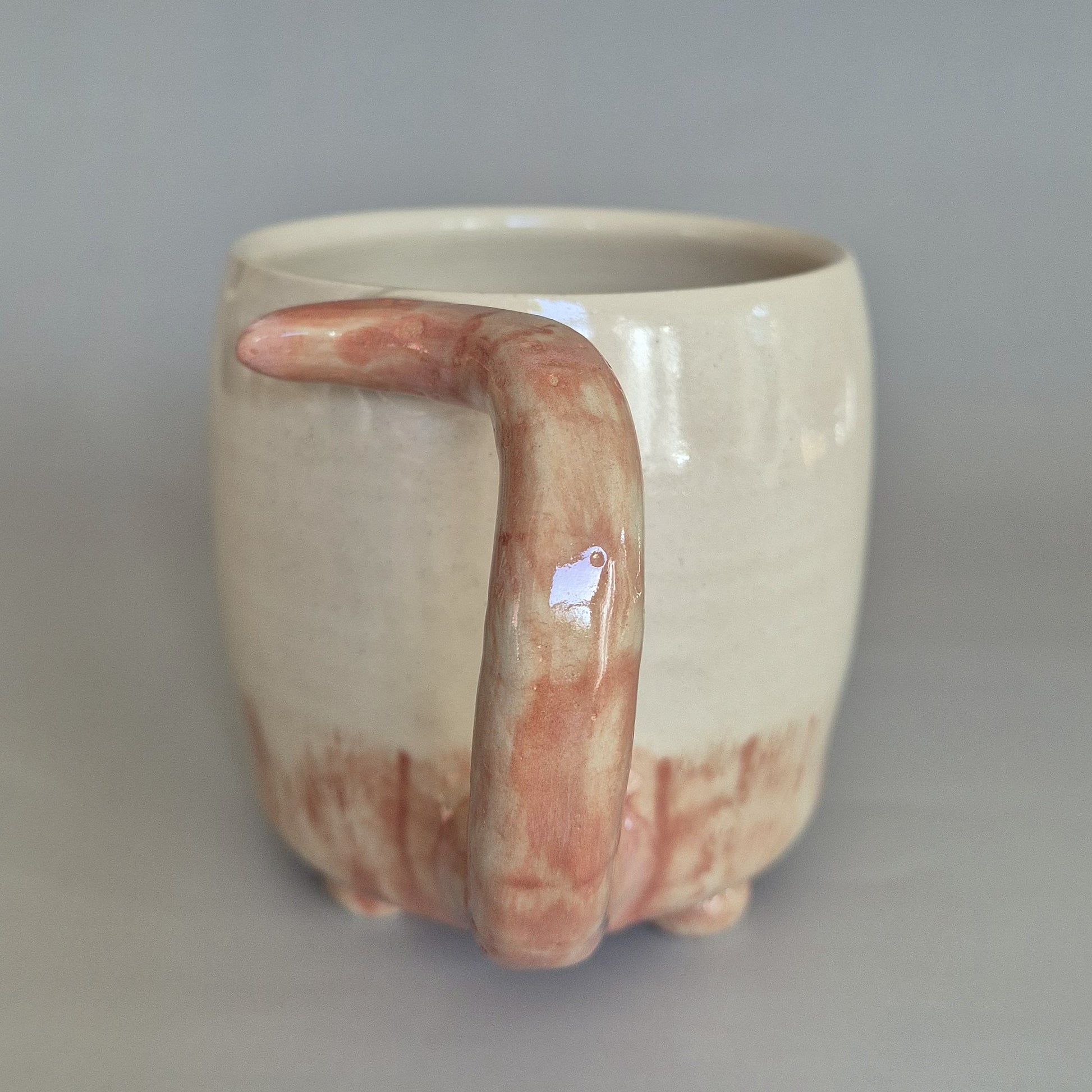 Ceramic mug with a unique handle on a plain background