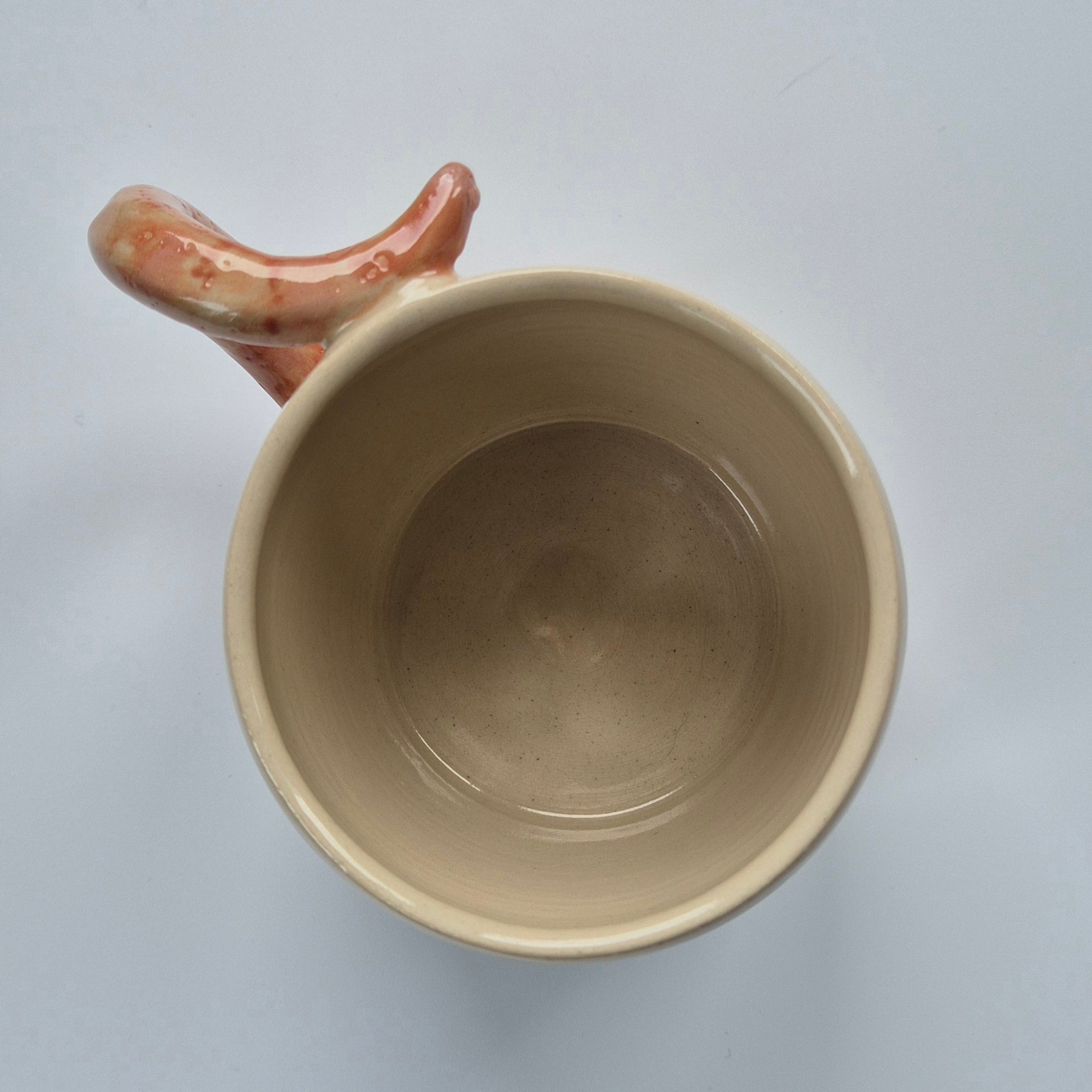 Ceramic mug with a unique handle on a light gray background