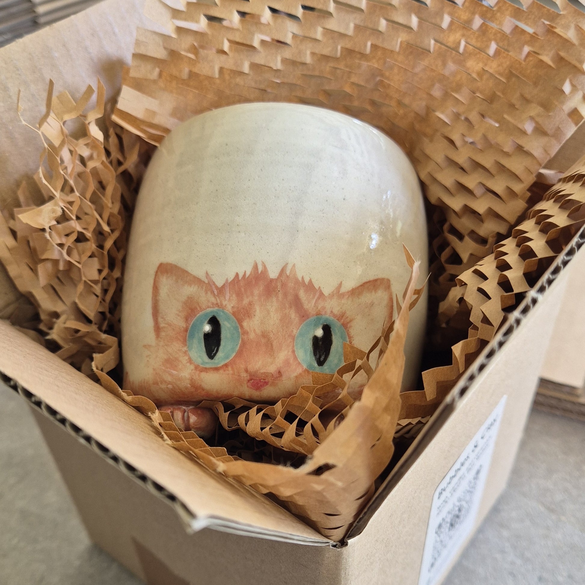Hand-painted Cat Mug - Amber - face up in a cardboard box