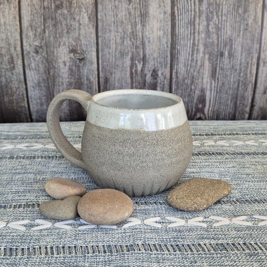 Ceramic mug with textured surface on a wooden table with stones