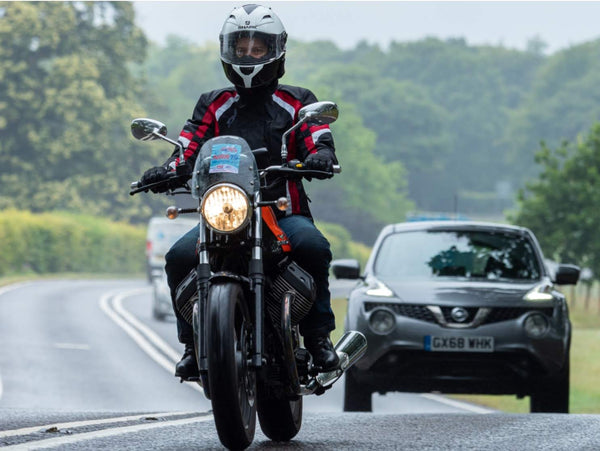 Kerry riding a motorcycle on a road with cars in the background