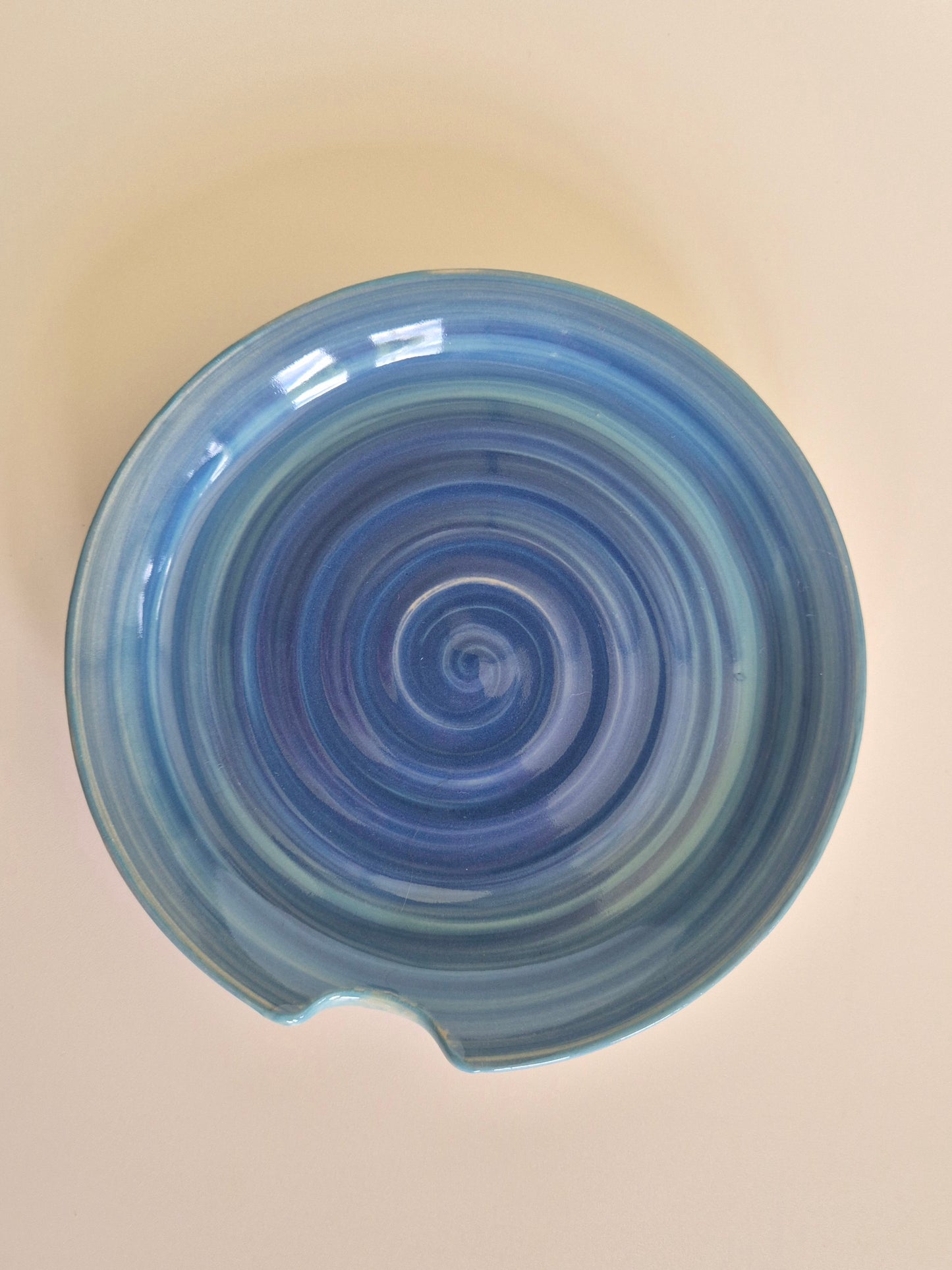 Blue spiral-patterned spoon rest on a beige background
